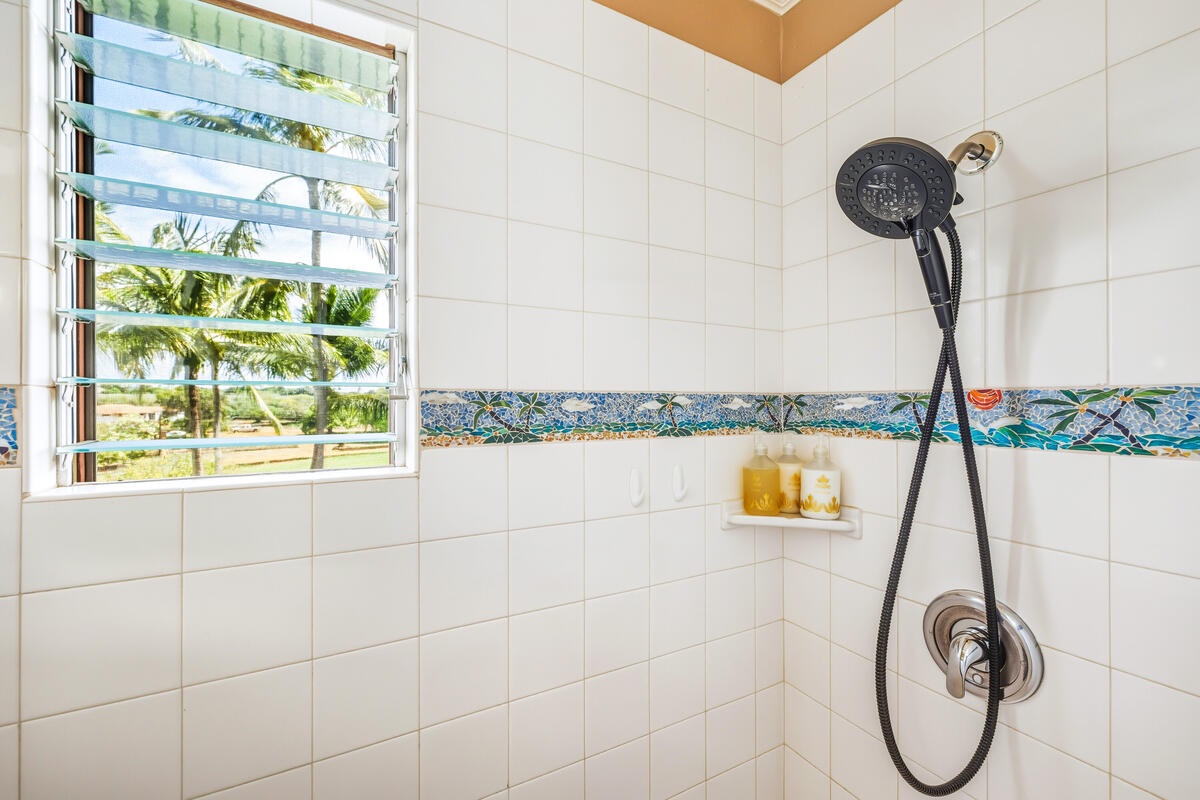 Step into your bright, tropical shower with stunning palm tree views through louvered windows and colorful tile accents.