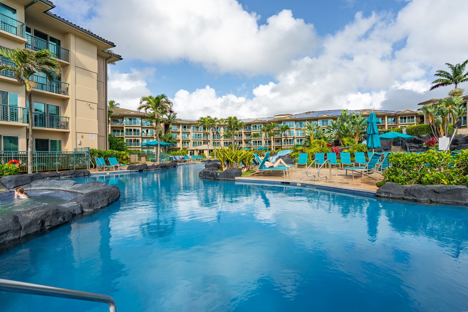 Sparkling resort pool surrounded by tropical palms and lounge chairs, offering a peaceful oasis under sunny skies—ideal for relaxing afternoons.