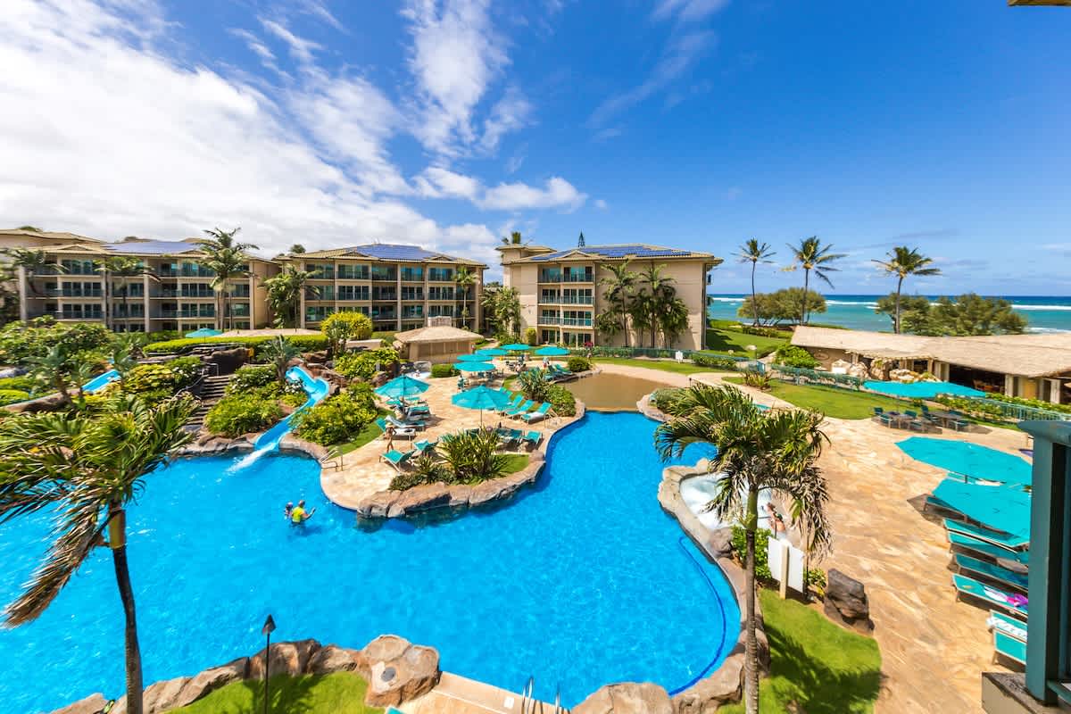 Beachfront resort featuring a stunning lagoon-style pool surrounded by tropical palms, sun loungers, and direct ocean access—your Hawaiian paradise awaits.