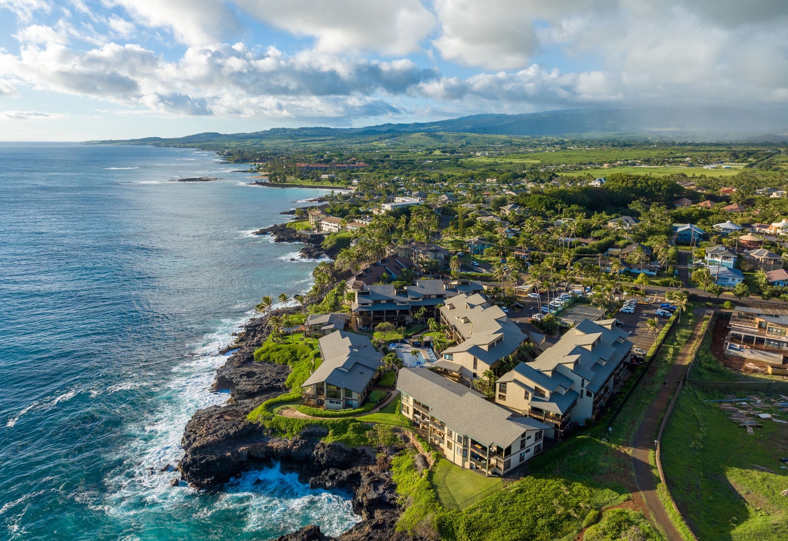 Stunning oceanfront property nestled along a dramatic coastline, showcasing lush tropical surroundings, rolling mountains, and pristine blue waters stretching to the horizon.
