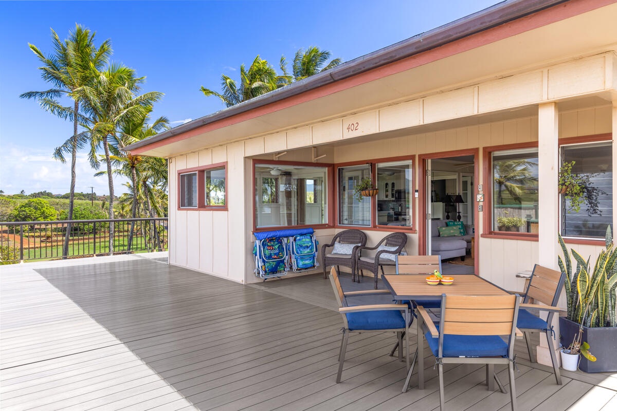Spacious deck with dining table overlooking tropical palms and open fields - your perfect spot for morning coffee and island breezes.