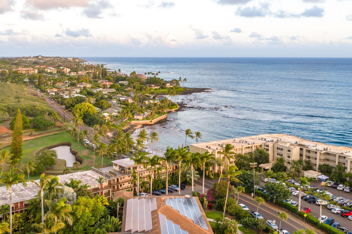 Stunning aerial view showcasing the tropical coastline with oceanfront properties, lush palm trees, and pristine beaches stretching along the scenic shoreline.