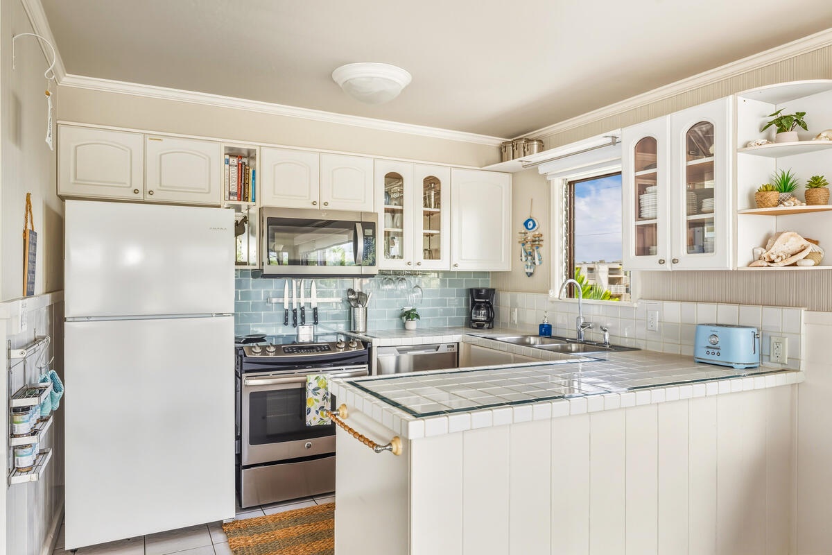 Your fully equipped kitchen features white cabinets, stainless appliances, and charming blue subway tile backsplash for delightful home cooking.