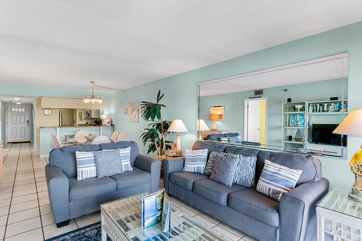 Relax in your spacious living area with comfortable blue sofas and soothing coastal colors that create a perfect beach getaway atmosphere.