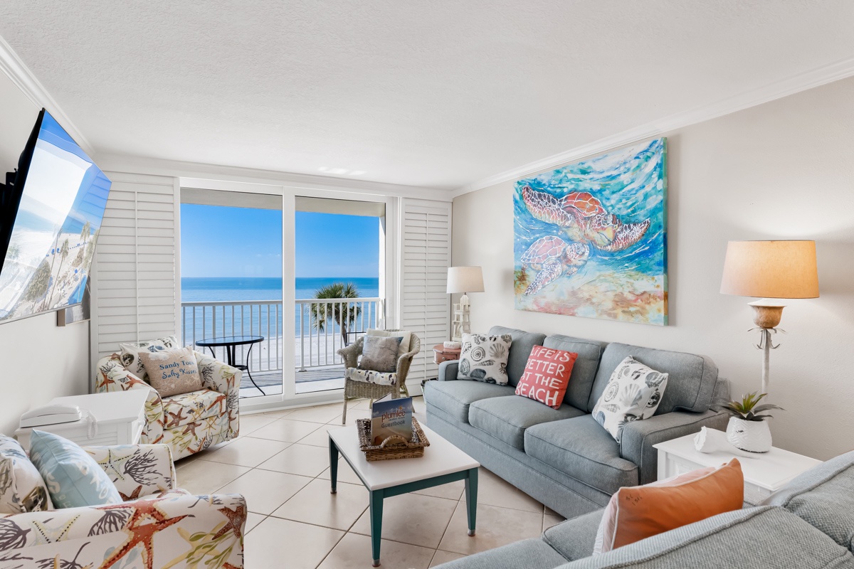 Your oceanfront living room features stunning sea views through floor-to-ceiling windows, comfortable seating, and coastal decor that brings the beach indoors.