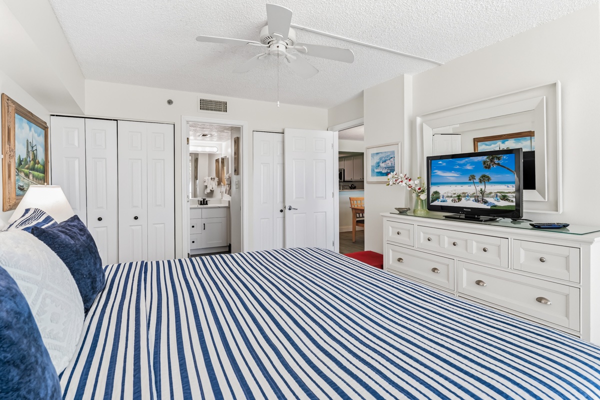 Slip into comfort with crisp linens and coastal charm. Your ceiling fan keeps things cool while you unwind, and thoughtful storage keeps everything within reach.