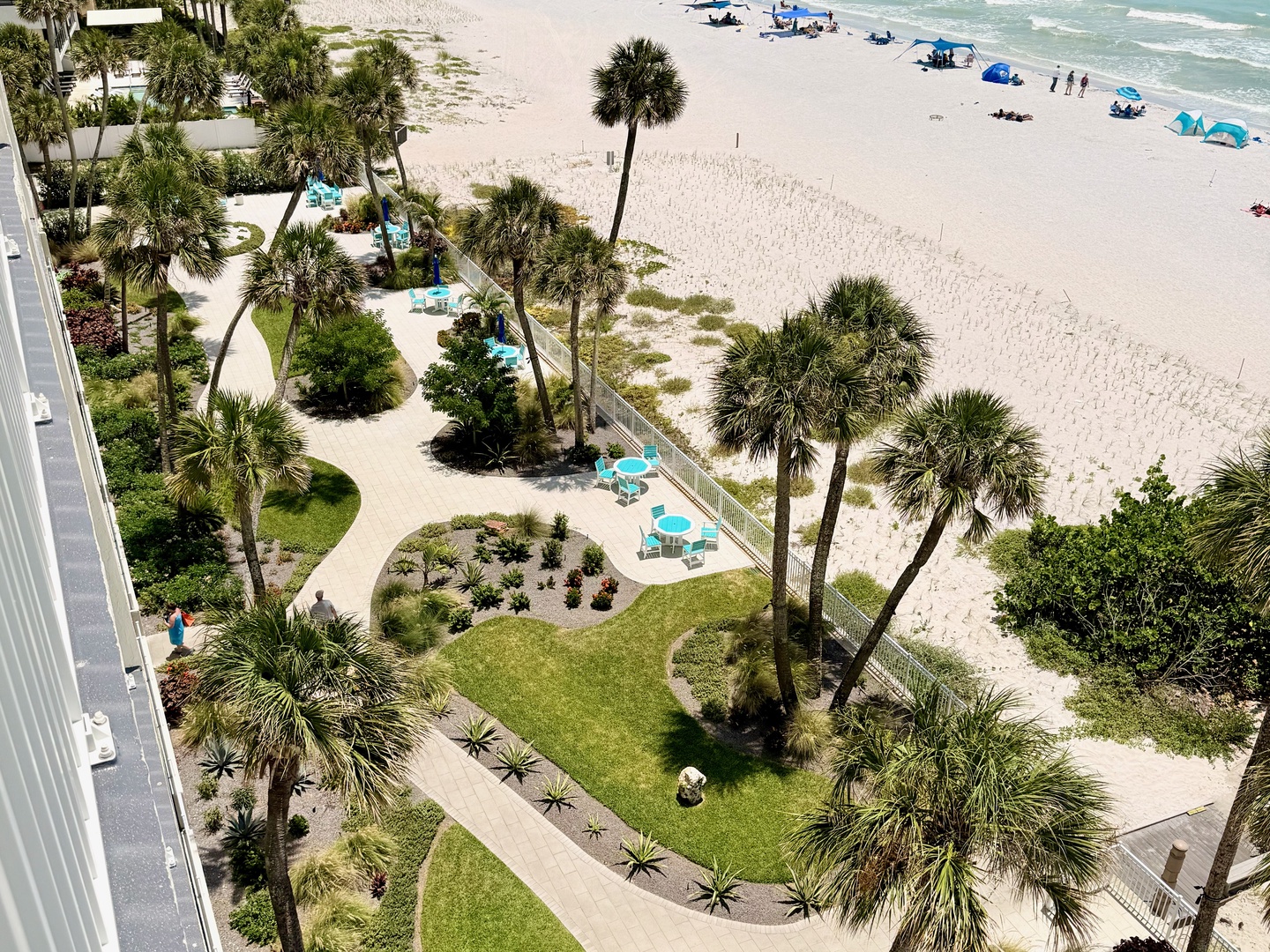 White sand beach stretches out to the Gulf, just steps from lush, landscaped gardens with swaying palms and turquoise seating areas perfect for soaking in your coastal escape.