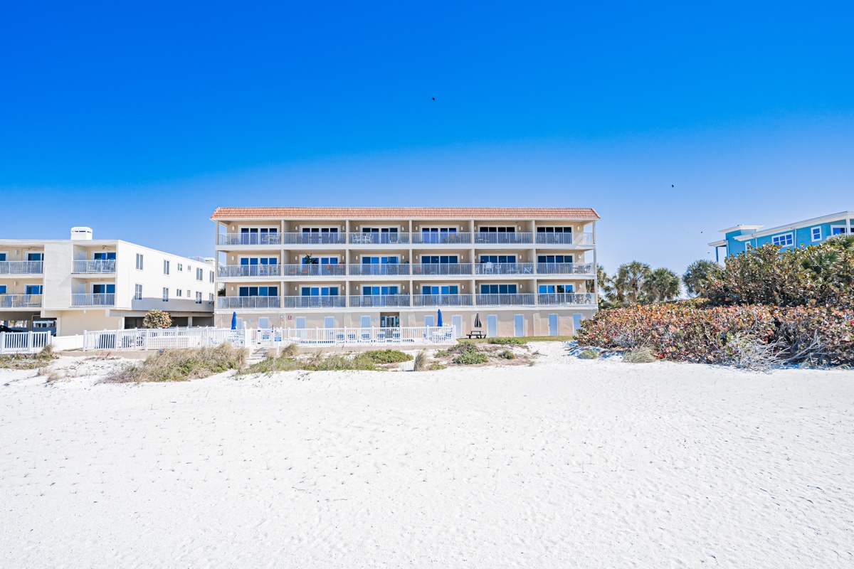 Beachfront property with direct beach access and stunning coastal views under clear blue skies.