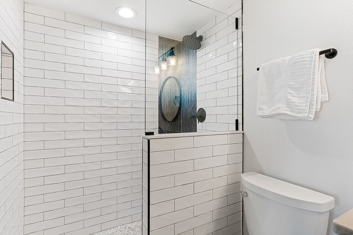 Unwind in your sleek bathroom featuring a rainfall shower, crisp subway tiles, and modern fixtures designed for your comfort.