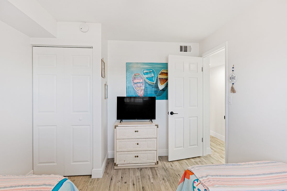 Your bright bedroom features charming coastal artwork and a flat-screen TV for cozy nights in after beachside adventures.