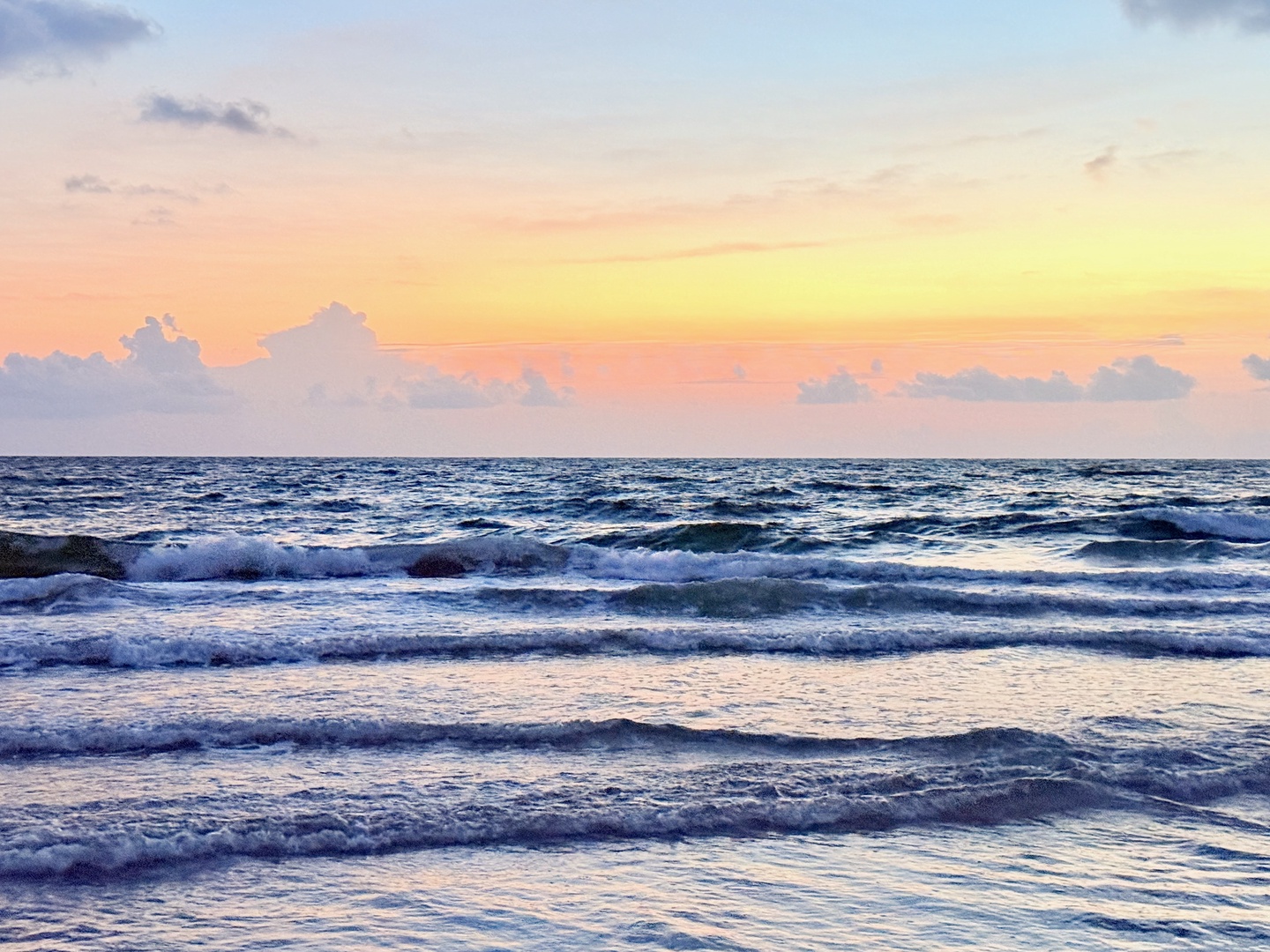 A stunning coastal sunrise paints the sky in soft pastels, with gentle waves rolling onto the shore—a serene setting for your morning retreat by the sea.