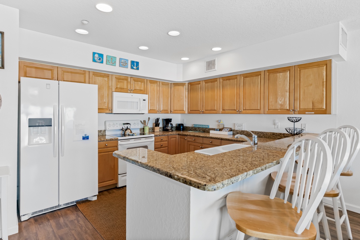 Your fully equipped kitchen features granite countertops, stainless steel appliances, and a breakfast bar perfect for morning coffee or casual meals.