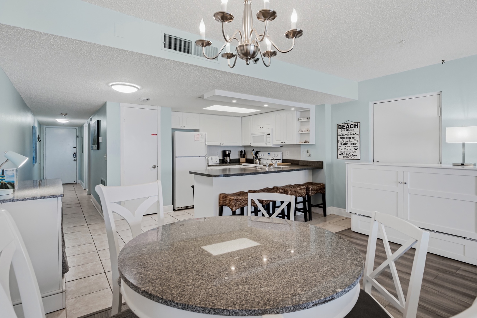 Gather around the spacious kitchen with granite countertops and breakfast bar, where mornings feel bright and breezy. Fresh white cabinetry and modern appliances make meal prep a pleasure in your coastal retreat.