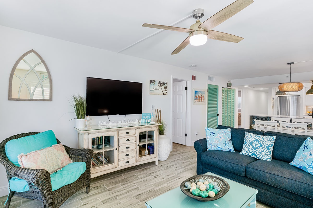 Relax in your bright coastal living room with comfy seating, beach-themed decor, and modern amenities for the perfect beach getaway.