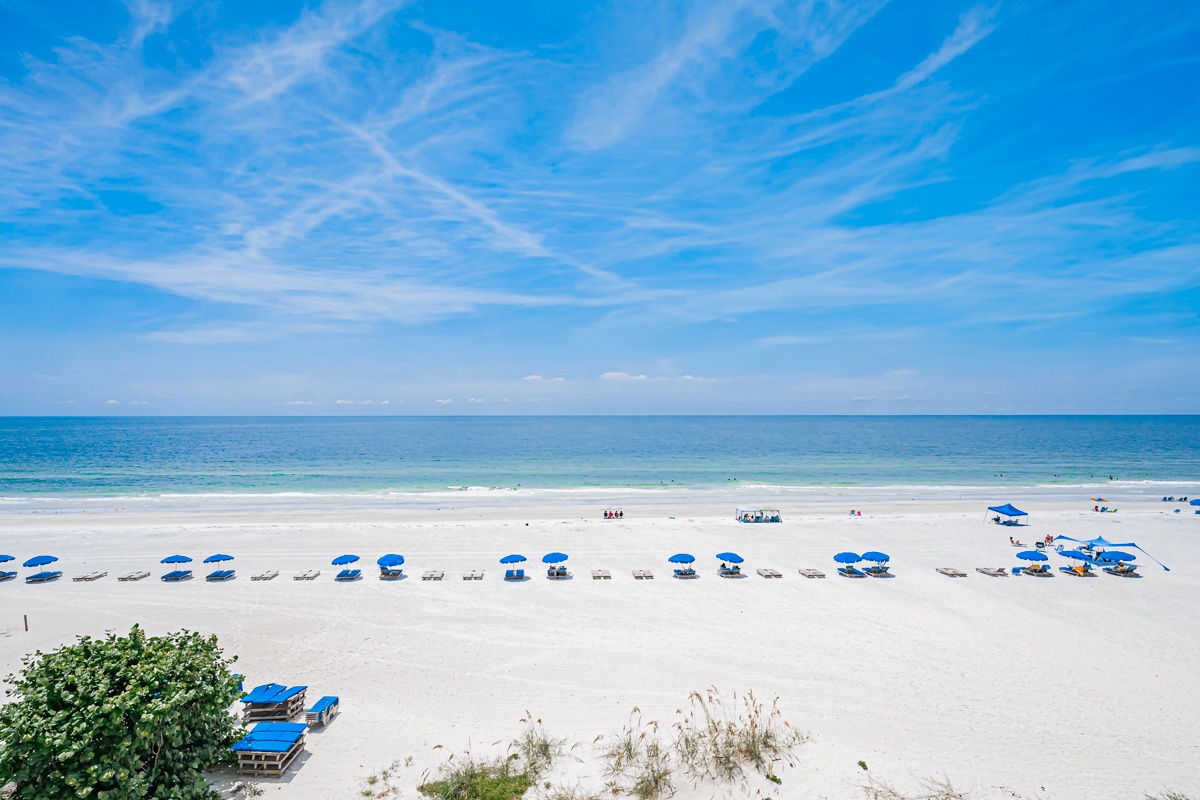 Pristine white-sand beach with gentle waves and vibrant blue skies creates an idyllic coastal setting for relaxation and seaside enjoyment.