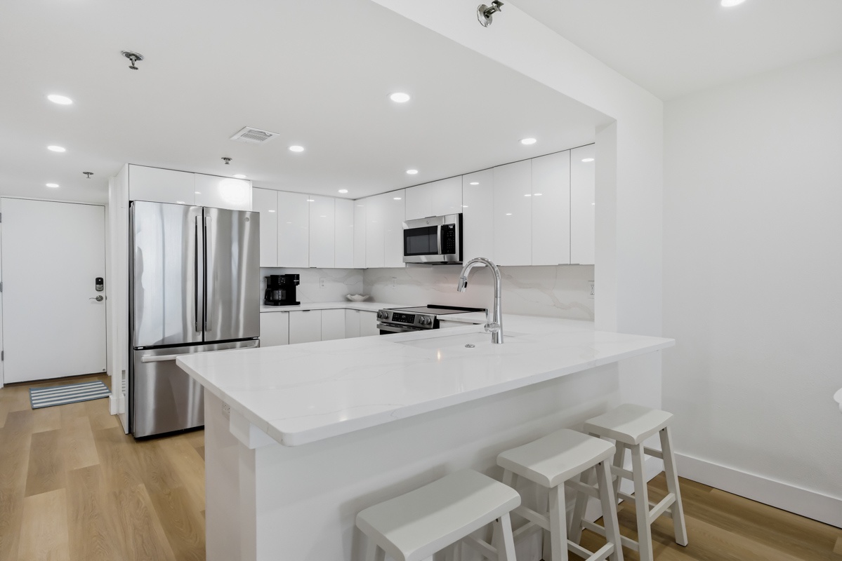 Your sleek white kitchen features modern appliances and a convenient breakfast bar for casual dining.