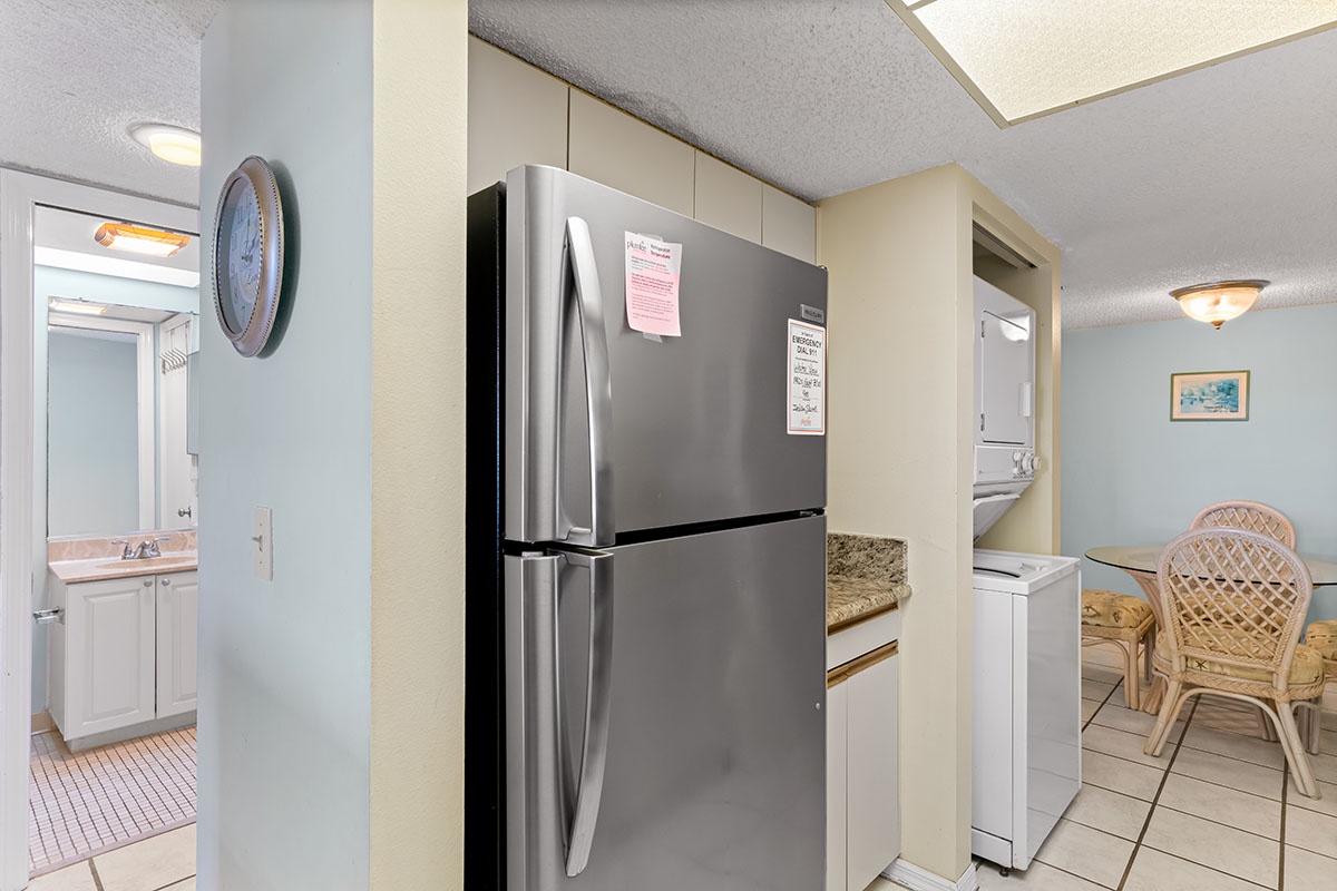 Your open-plan kitchen features stainless steel appliances, warm tile floors, and coastal-inspired decor perfect for preparing vacation meals.