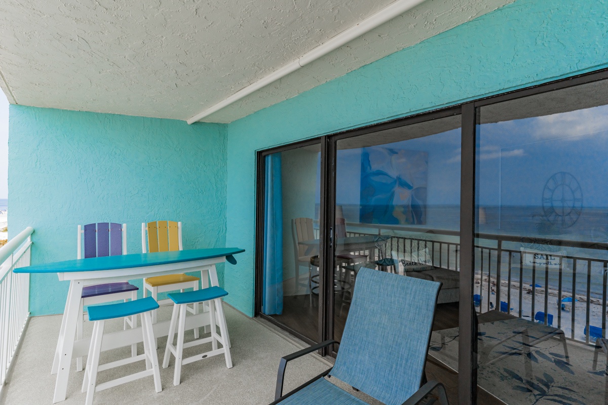 Your private oceanfront balcony features colorful dining chairs and a cozy lounge spot where you can savor morning coffee while watching the waves.
