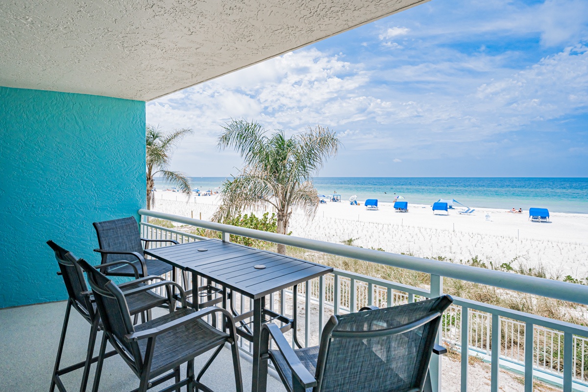 Beachfront balcony offers unobstructed views of white sand and turquoise waters, with bistro-style seating perfect for morning coffee or evening cocktails.