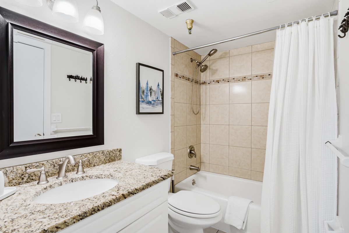 Your pristine bathroom features elegant granite countertops, spacious tub-shower combo, and fresh white linens waiting for your arrival.
