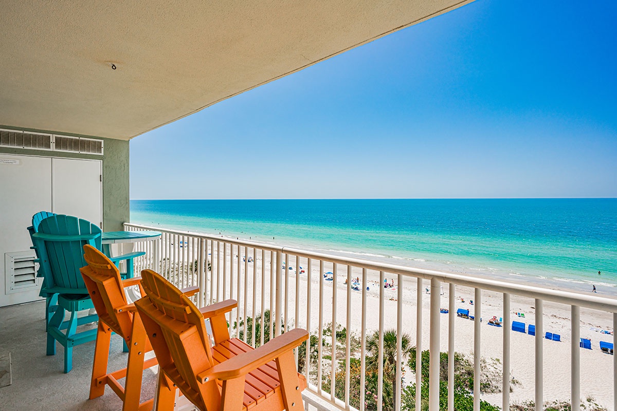 Unwind in your private oceanfront retreat with colorful beach chairs and endless azure waters stretching before you.