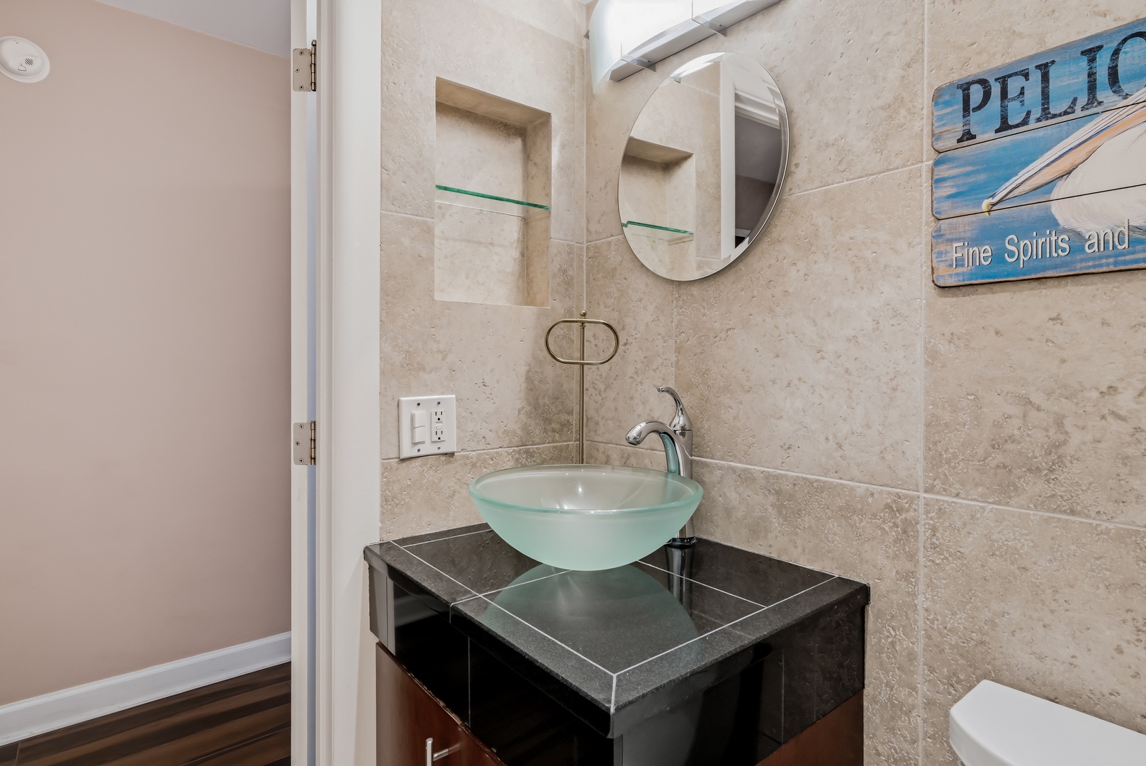 This sleek bathroom features neutral tile, a modern glass vessel sink, and coastal-inspired décor—perfect for freshening up during your stay.