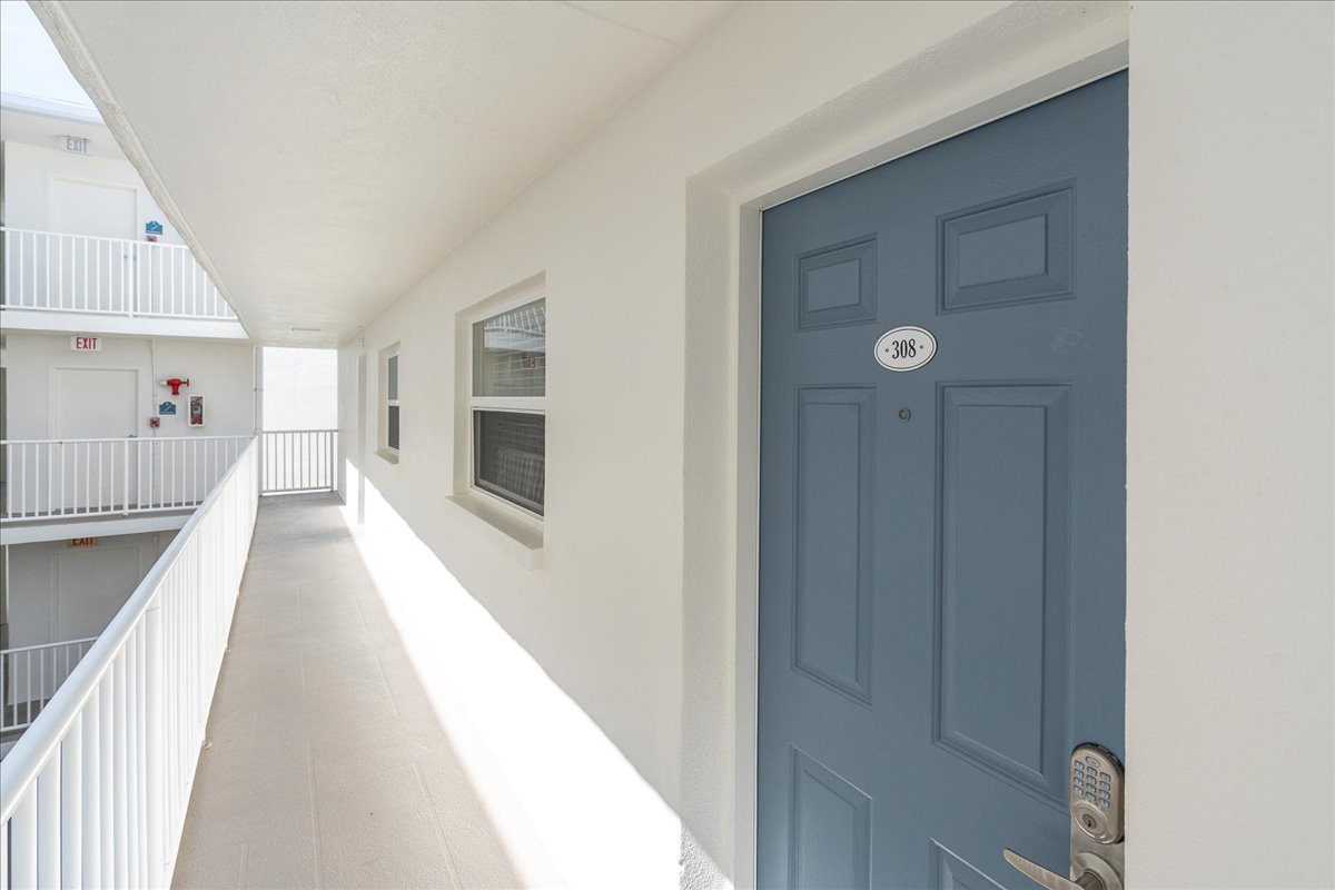 The hallway leading to unit 308 features clean, bright architecture with vaulted ceilings and natural light—a welcoming arrival to your coastal retreat.