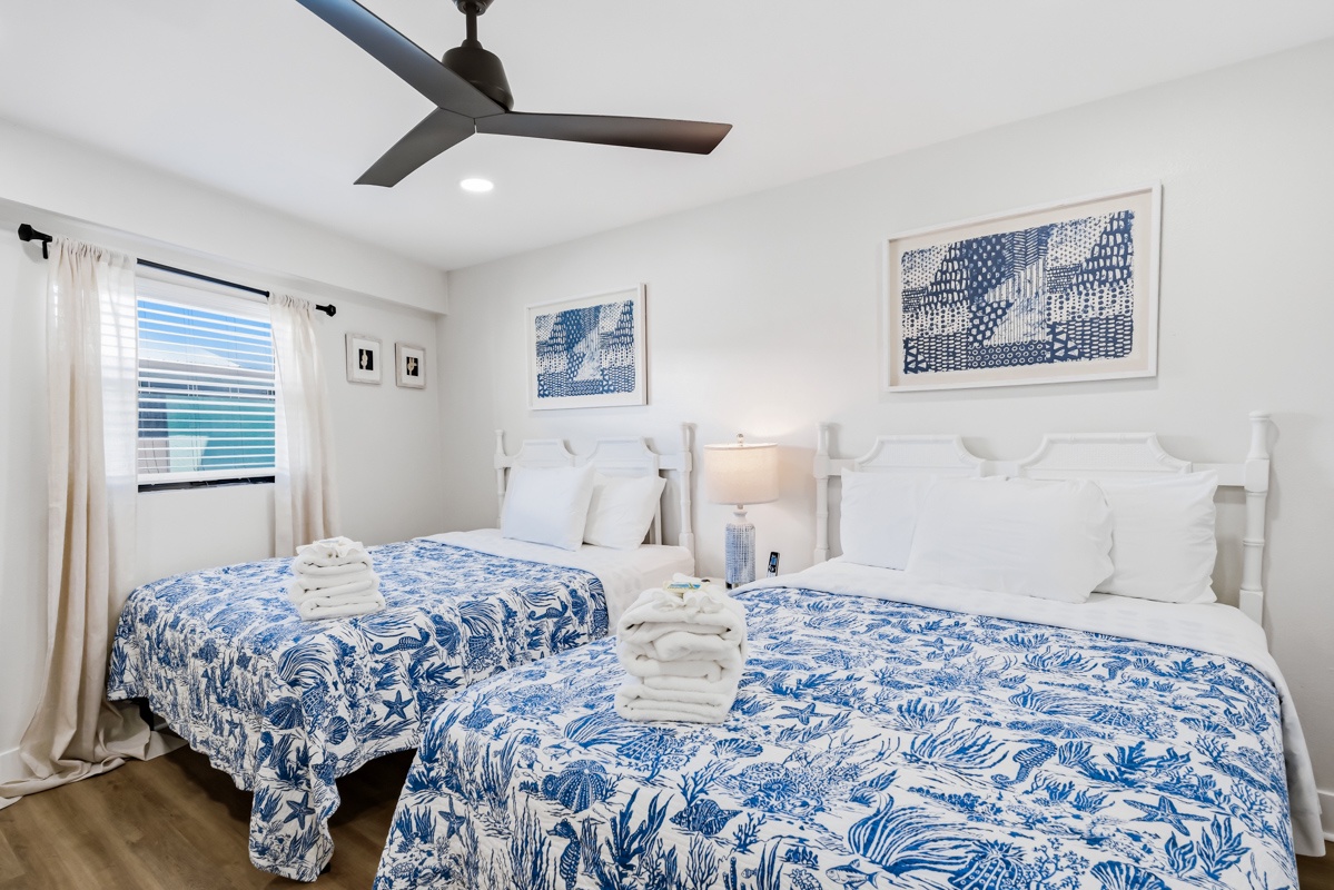 Your serene 2 Queen bed bedroom features coastal blue linens, fresh towels, and ocean-inspired art to help you unwind after sunny beach days.