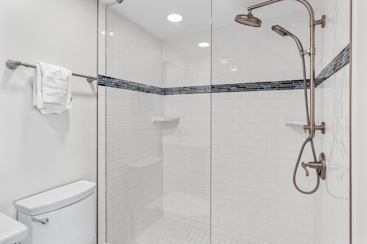 Step into your spa-like shower with elegant subway tiles, dual rainfall heads, and fresh towels waiting nearby.