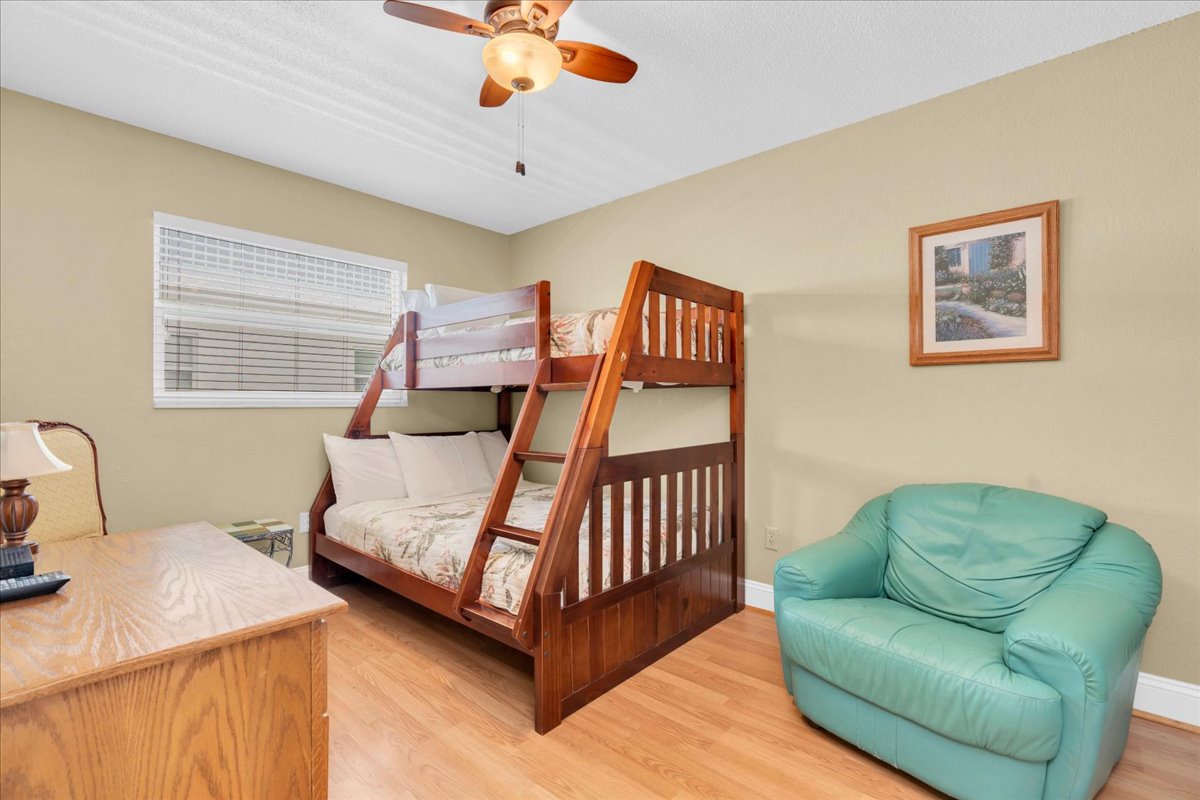 Your family can unwind in this cheerful bedroom featuring a sturdy Full/Twin bunk bed for the kids and a cozy chair to curl up in—with warm lighting and bright windows creating the perfect space for rest.