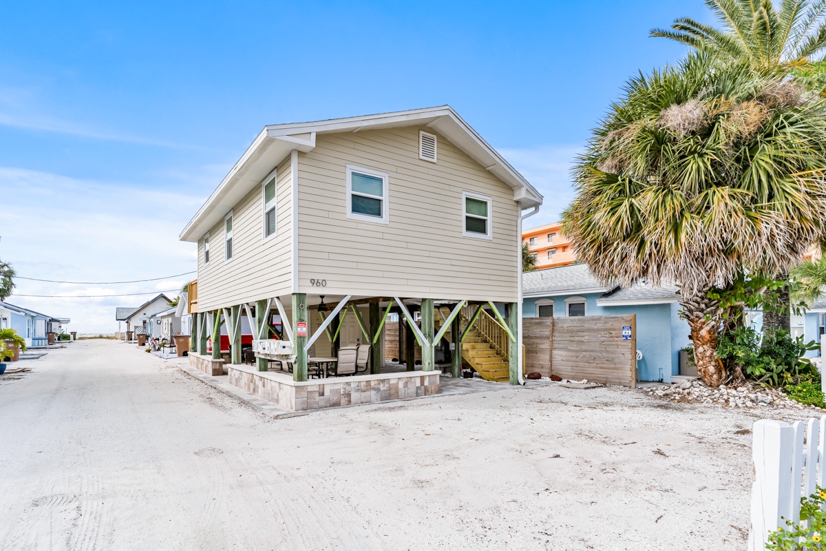 Charming beachside home on stilts with covered outdoor living space and tropical landscaping in a peaceful coastal neighborhood.