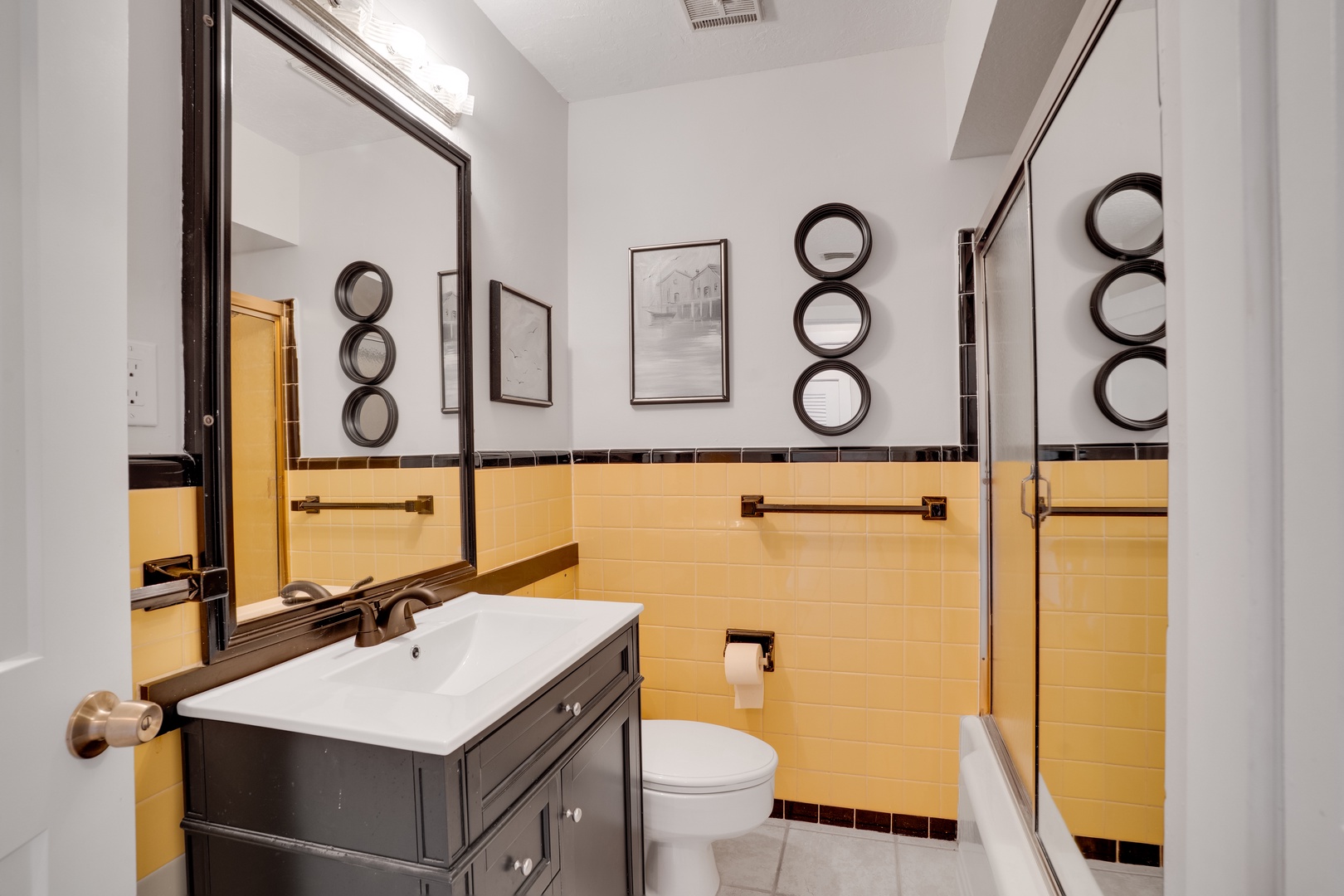 Step into your stylish bathroom with warm yellow tiles and elegant dark accents that create a welcoming vintage charm.
