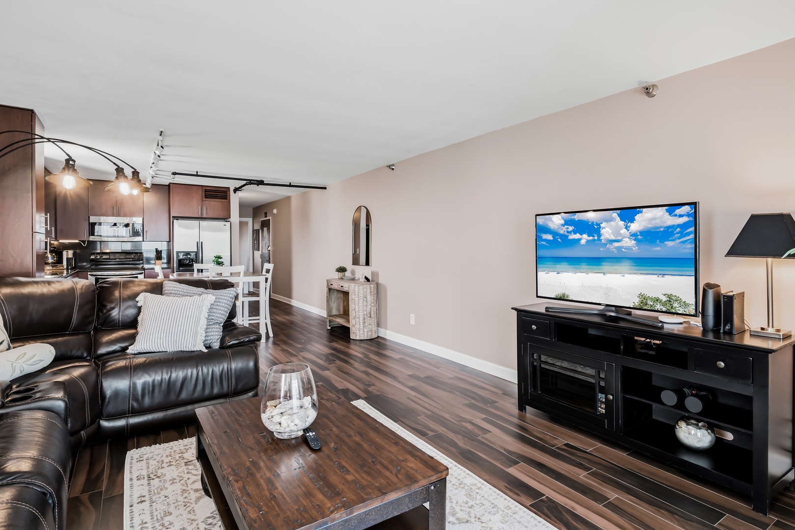 Unwind in your spacious living area with rich wood floors, plush leather seating, and modern entertainment—perfect for cozy evenings after exploring the coast.