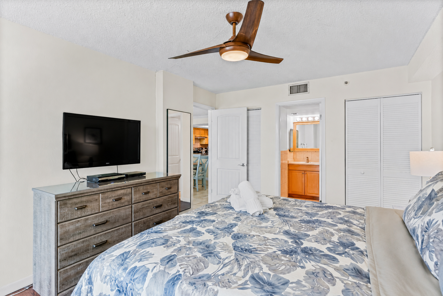 Primary bedroom with ceiling fan and TV