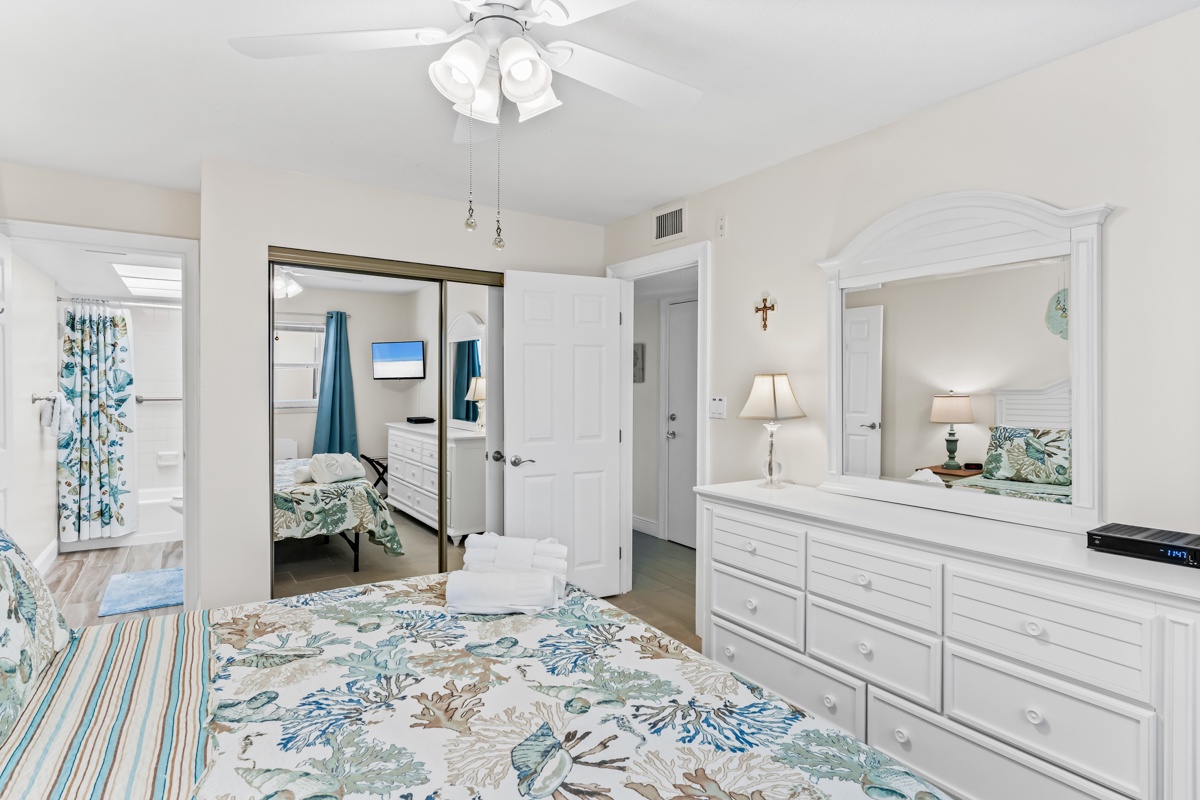 Your bright master bedroom features coastal florals, mirrored closets, and convenient dresser storage for a relaxing coastal getaway.