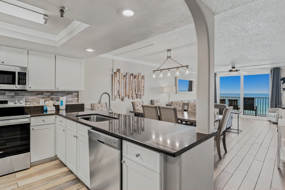 Step into your fully equipped kitchen with granite countertops and modern appliances, flowing seamlessly into the dining and living area with breathtaking ocean views through the balcony doors.