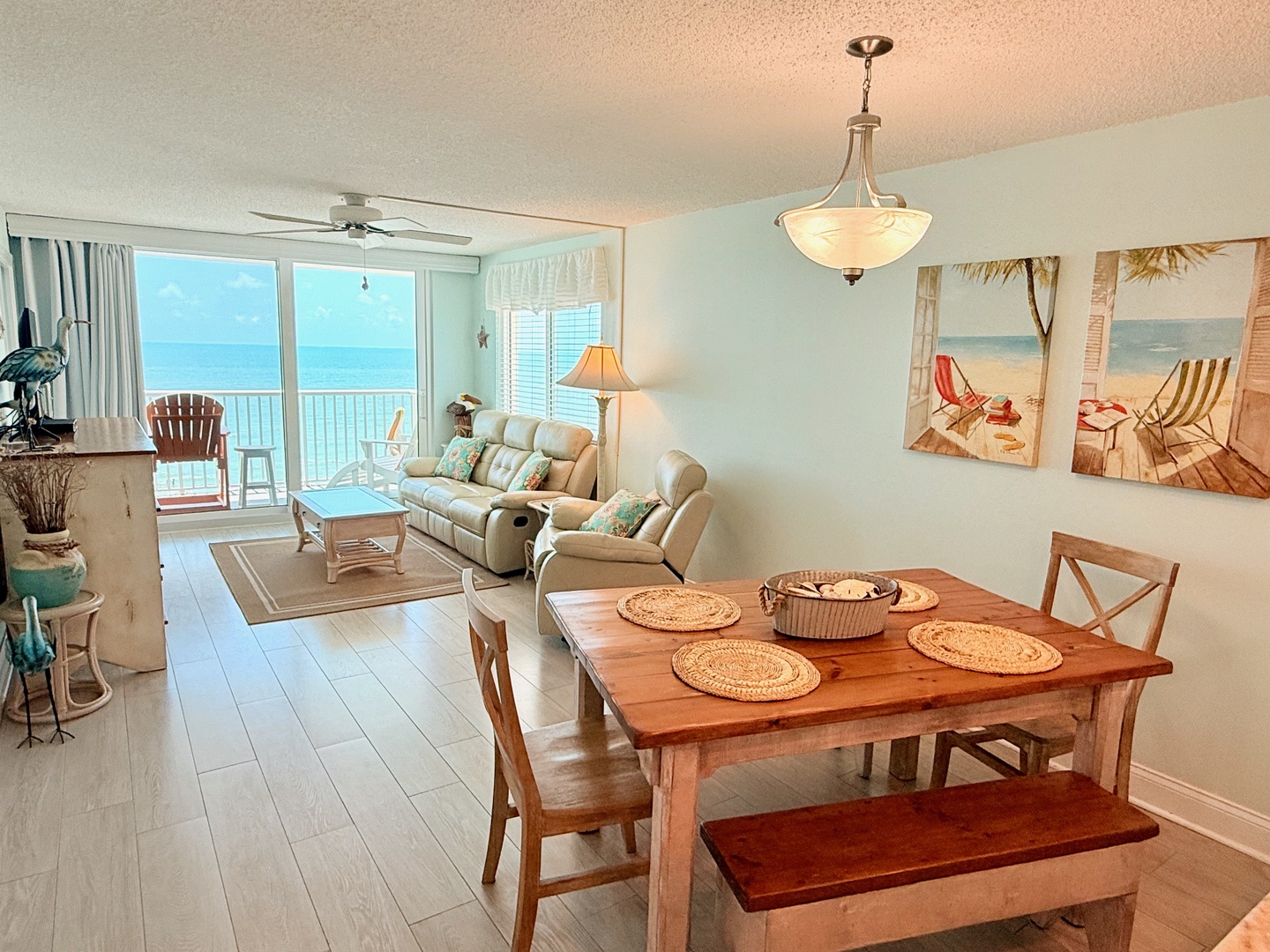 Step into your bright coastal retreat, where ocean views greet you through expansive glass doors and soft natural light fills every corner. Gather at the farmhouse table or sink into plush seating while waves shimmer just beyond your private balcony.