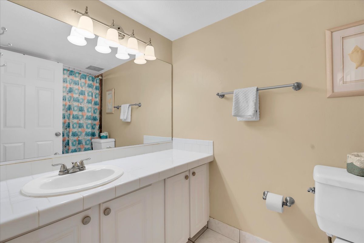 This bright bathroom offers a spacious vanity, fresh towels, and a cheerful shower curtain—your refreshing retreat after a day of coastal adventures.