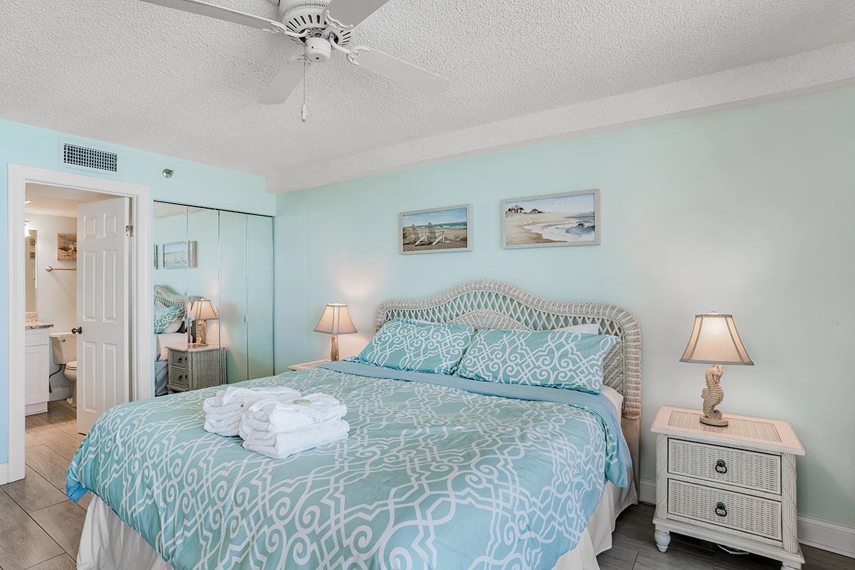 Slip into your coastal retreat with soft aqua walls and a plush bed adorned with fresh towels, where ocean breezes await.