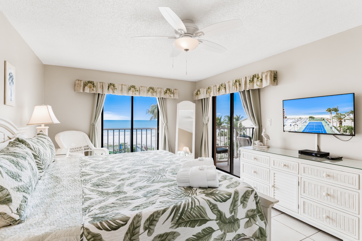 Wake up to stunning ocean views from your comfortable bed, where tropical-themed linens complement the breathtaking beachfront panorama beyond your private balcony.