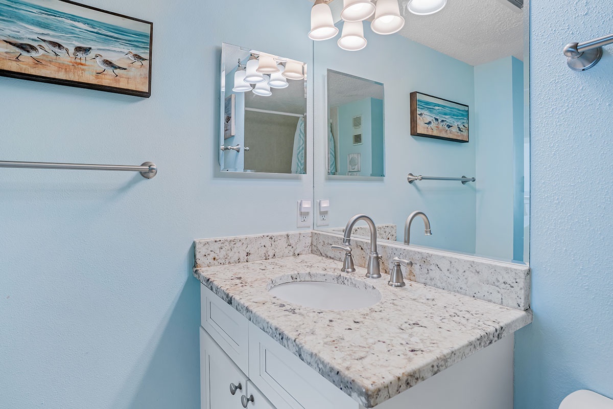Your coastal-themed bathroom features granite countertops and peaceful ocean artwork, creating a serene space to refresh during your stay.