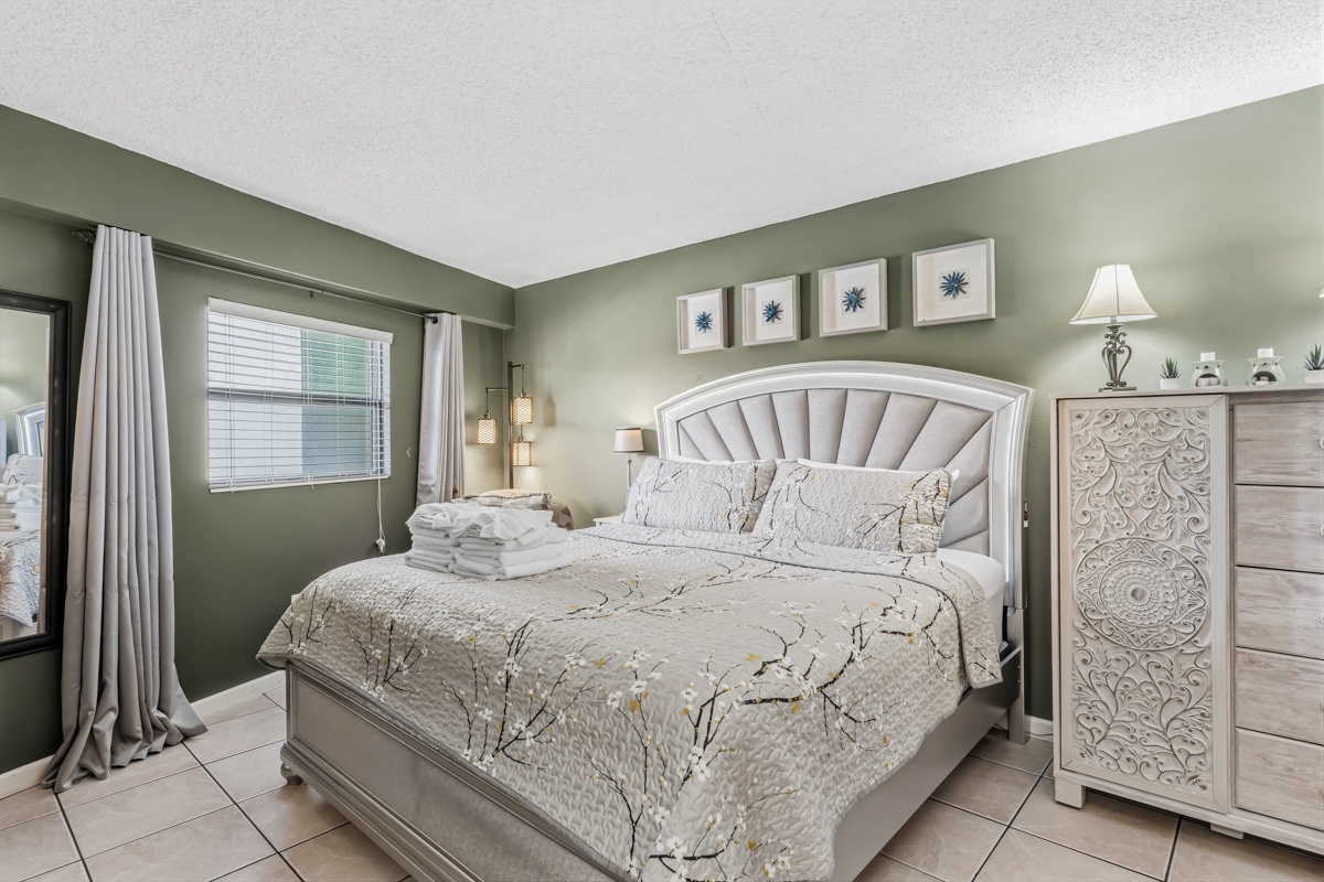 Unwind in your serene bedroom with calming sage tones, a plush upholstered bed dressed in soft linens, and elegant decor that creates your perfect retreat.
