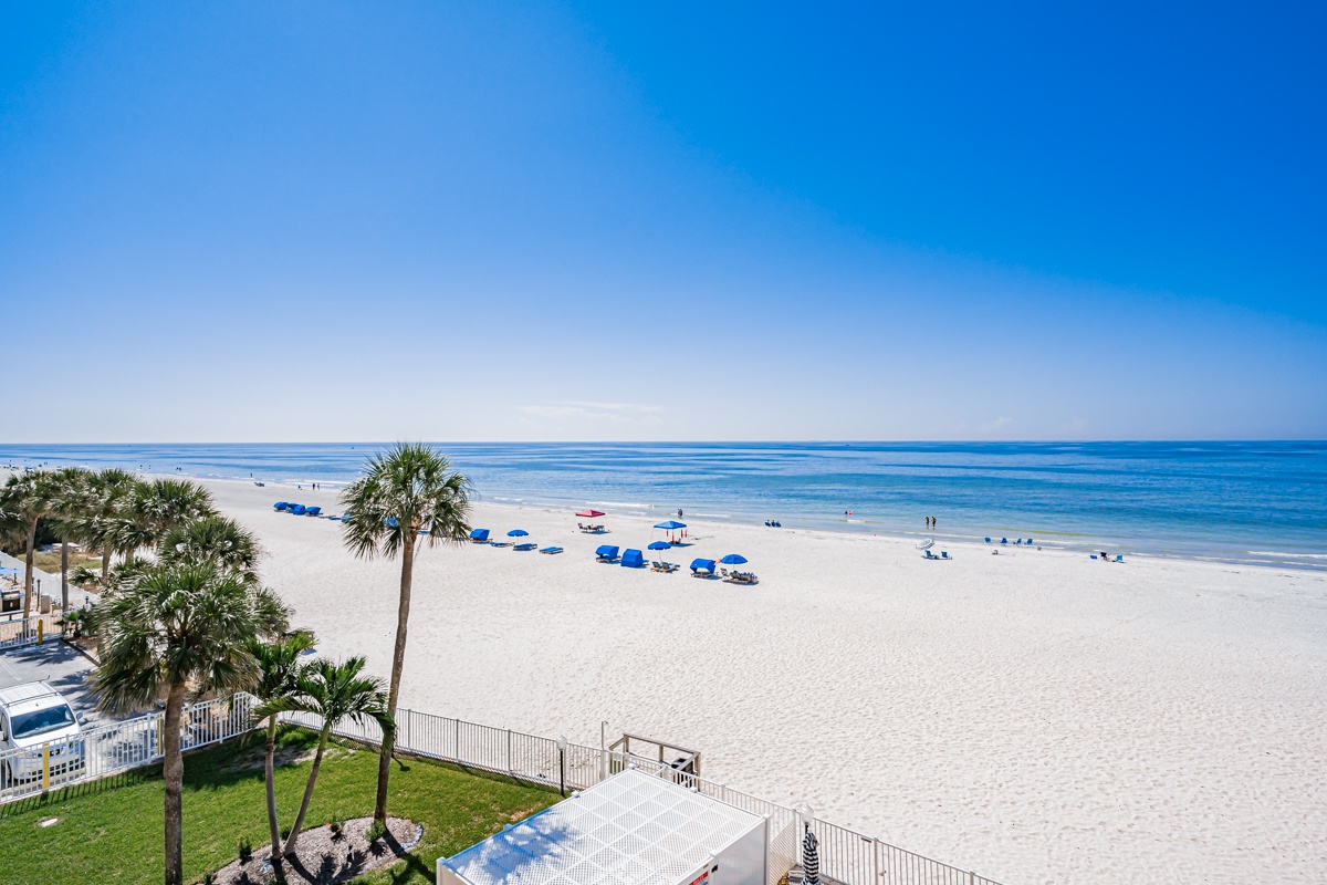 White sands stretch endlessly beneath endless blue skies, where gentle waves meet the shoreline and palm trees sway in the coastal breeze—your perfect escape just steps away.