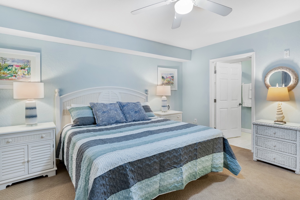 Drift off in your serene coastal King bedroom with soothing blue hues, crisp white furnishings, and gentle ceiling fan creating the perfect oceanside retreat.
