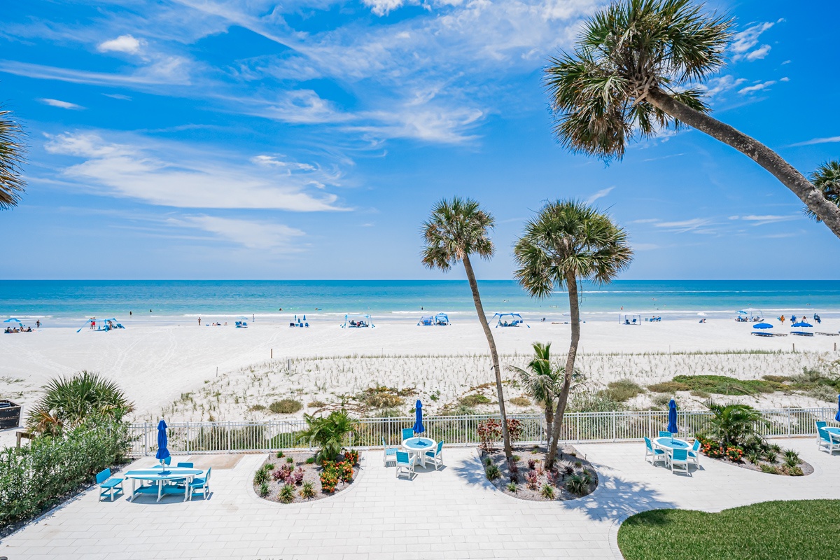 A pristine beachfront setting with swaying palms, vibrant landscaping, and direct access to soft white sands and turquoise waters. The perfect coastal escape awaits just steps from your door.