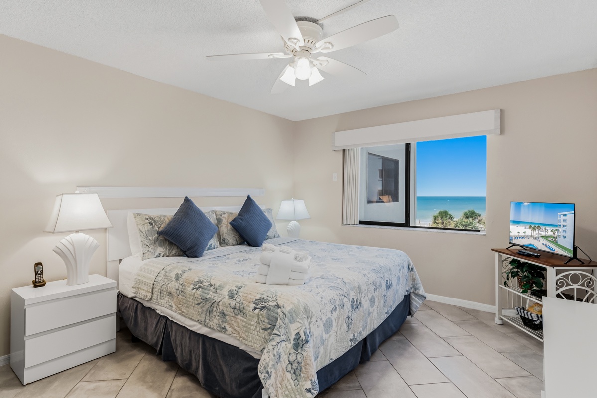 Wake up to brilliant ocean views framing your window, where soft breezes from the ceiling fan and coastal sunlight create your perfect beach getaway.