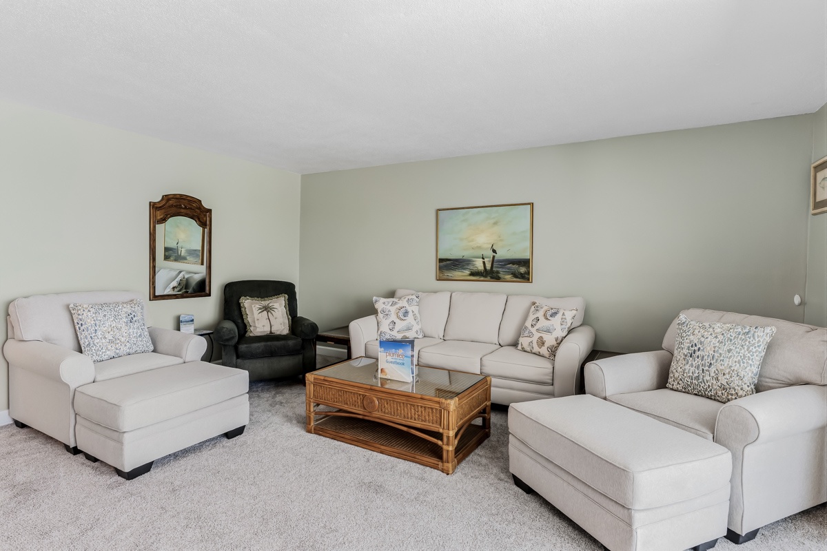Sink into plush cream sofas and unwind in your light-filled living space, where coastal touches and comfortable seating invite you to relax after a day at the beach.