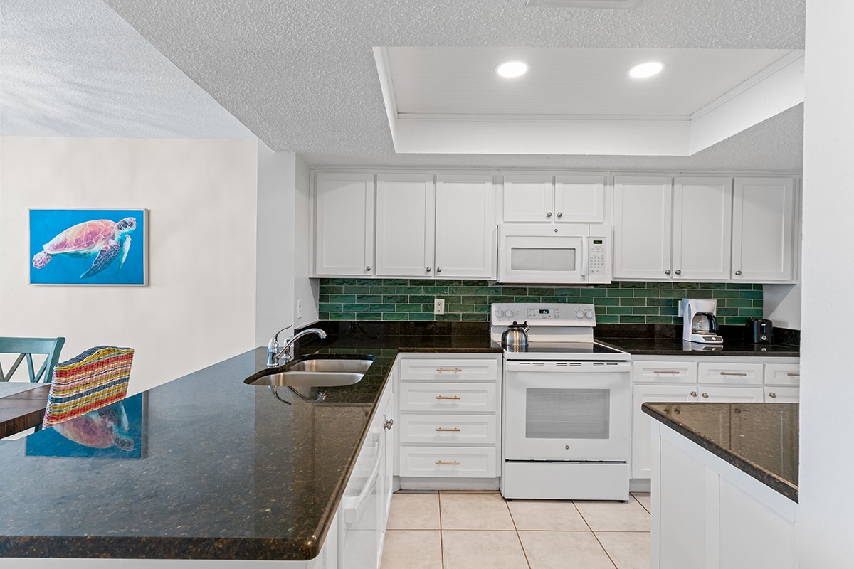 Your fully equipped kitchen awaits with granite counters, white cabinets, and colorful tile backsplash—perfect for preparing meals during your stay.