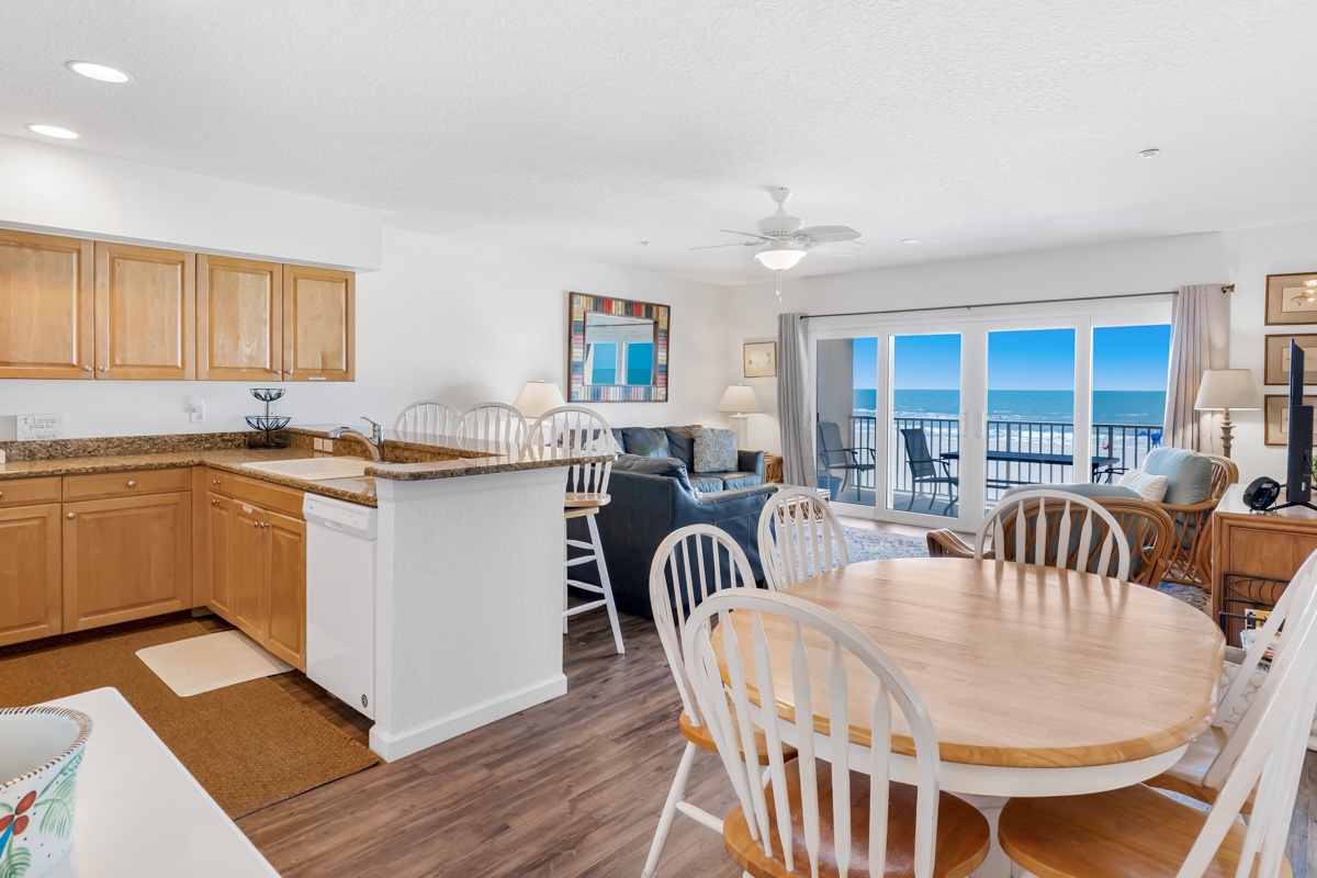 Your open-concept kitchen flows seamlessly into the dining area, where ocean views through expansive windows create the perfect backdrop for memorable meals.
