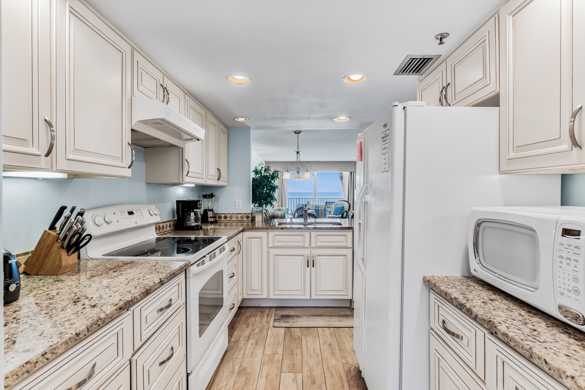 Your fully equipped kitchen is ready for every meal, with ample counter space, modern appliances, and granite countertops. Through the open layout, you'll catch glimpses of the ocean view beyond.